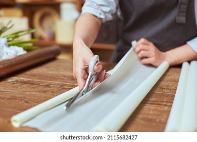 Close Up Of Female Florist Hands Cutting Color Wrapping Paper With Scissors For Freshly Made Bouquet In The Flower Shop