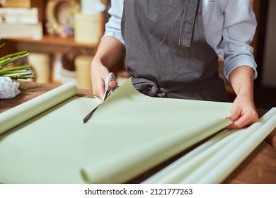 Close Up Of Female Florist Hands Cutting Color Wrapping Paper With Scissors For Freshly Made Bouquet In The Flower Shop