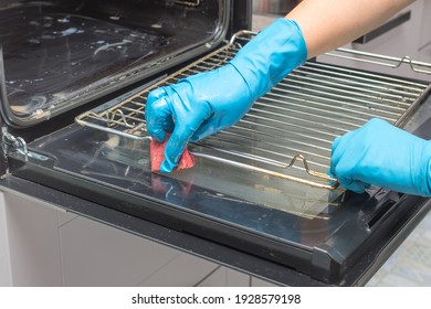 Close Up Of Female Hand With Blue Protective Gloves Cleaning Oven 