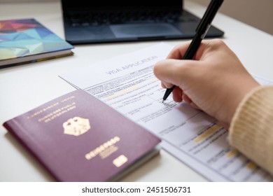 Close up of female hand filling out a visa application document with a German passport, blurry background 