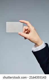 Close Up Of Female Hand Holding Business Card Mockup To Camera Against Grey Background