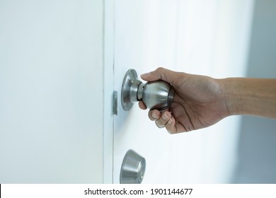 close up female hand holding a door knob or door handle in a house