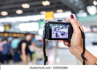 close up of female hand holding DSLR digital camera among the crowd at airport - Shutterstock ID 1350931886