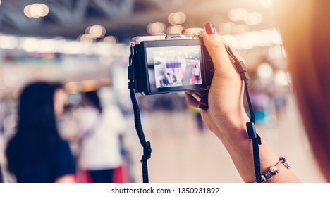 close up of female hand holding DSLR digital camera among the crowd at airport - Shutterstock ID 1350931892