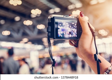 close up of female hand holding DSLR digital camera among the crowd at airport - Shutterstock ID 1378448918