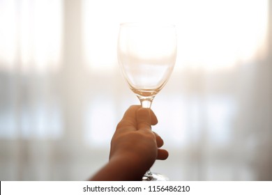 Close Up Of Female Hand Holding Empty Clean Transparent Wine Glass.