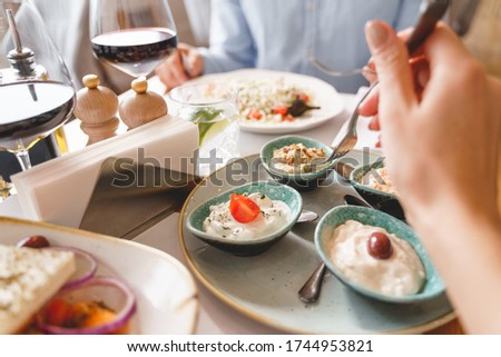 Close up of female hand holding fork while sitting at the table with set of cream food for adding flavor, moisture, and visual appeal to dish