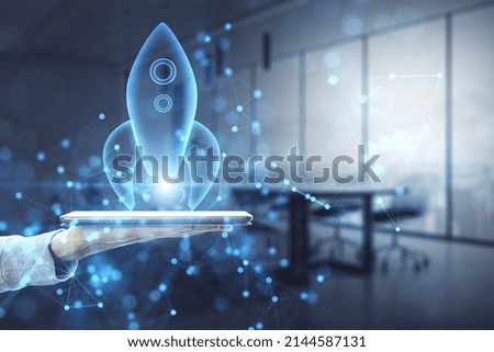 Close up of female hand holding phone with abstract glowing blue rocket space ship on blurry office interior background. Startup and company growth concept. Double exposure