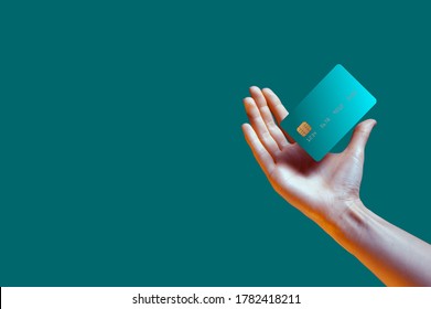 Крупным планом женская рука держит левитирующий шаблон макет банковской кредитной карты с онлайн-сервисом, изолированным на зеленом фоне