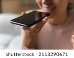 Close up female hand holds smartphone near mouth using speakerphone, send audio voice message to friend, using virtual assistant, talking through loudspeaker easy advanced usage of modern tech concept