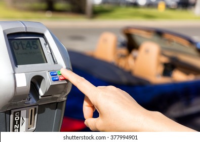 Close up of female hand, index finger, selecting parking meter time outdoors on street. Selective focus on tip of index finger and meter buttons. 