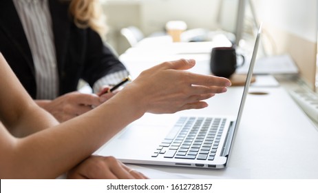 Close up female hand pointing on pc screen talking with teammate discuss project during busy fruitful workday seated at workplace desk, teamwork, help intern with corporate app or new software concept