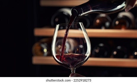 Close up female hand pouring red wine to glass. Wine expert, sommelier tasting, rating and drinking wine, bottles in background. Restaurant, wine bar, waitress. - Shutterstock ID 2252918273
