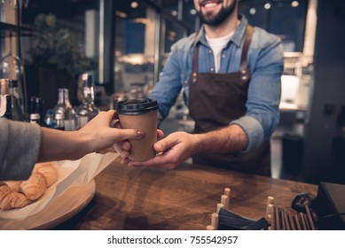 Close up female hand taking cup of hot coffee from barista in confectionary shop. Purchase concept - Powered by Shutterstock