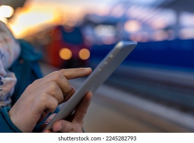 Close up of female hand using tablet on railway station while waiting train in winter time