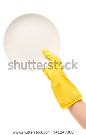 Close up of female hand in yellow protective rubber glove holding clean white plate against white background