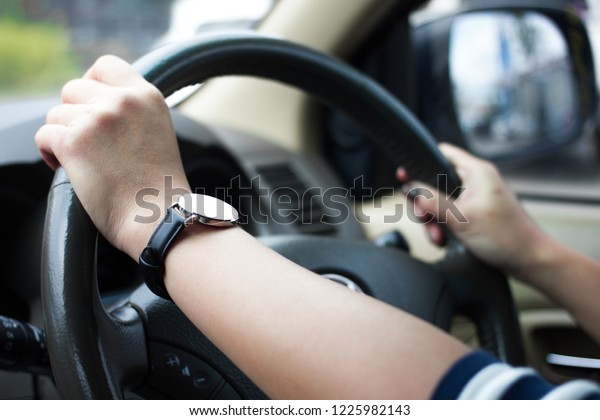 Close up of female\
hands with a clock on the steering wheel of a car while driving,\
working age concept