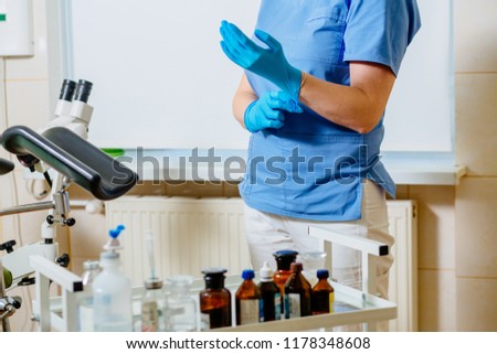 Close up of female hands - doctor gynecologist dressed blue gloves at gynecological room at medical center.