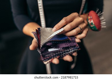 Close Up Of Female Hands Holding Fabric Swatches. Focus On Female Hands Selecting A New Fabric From Different Samples.