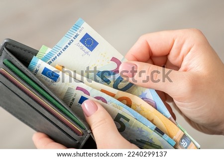 Close up of female hands holding grey wallet with 20 and 50 euro banknotes. Purchases, business, finances concept