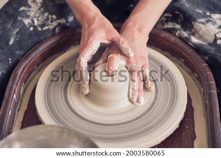 Similar – Young female sitting by table and making clay or ceramic mug