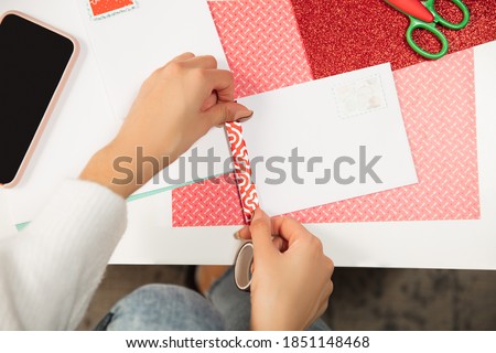 Close up female hands making greeting card for New Year and Christmas 2021 for friends or family, scrap booking, DIY. Writing a letter with best wishes, design her homemade card. Holidays, celebration