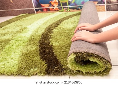 Close Up Of Female Hands Rolling Green Feathery Carpet For Cleaning. Side View.