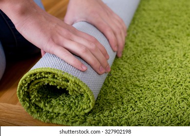 Close Up Of Female Hands Rolling Green Fluffy Carpet For Cleaning