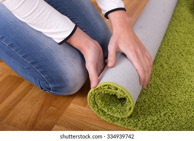 Close Up Of Female Hands Rolling Green Fluffy Carpet For Cleaning