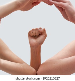 Close Up Of Female Hands Showing Feminist Sign. Raised Fist Framed By Hands Of Women Isolated Over White Background. Feminism, Equality And Liberation Concept