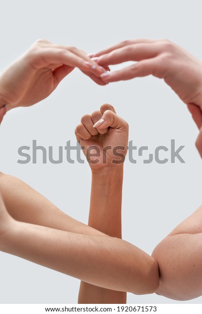 Close up of female\
hands showing feminist sign. Raised fist framed by hands of women\
isolated over white background. Feminism, equality and liberation\
concept. Vertical shot