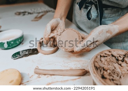 Close up of female hands working with clay in a workshop. Selective focus.