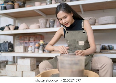 Close Up Of Female Hands Working On Potters Wheel,asian Female Sculpture Woman Shaping Mold Small Vase Bowl Clay On Potter's Wheel At Home Studio Workshop Art And Creation Hobby Concept