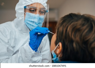 Close up of female health Professional in PPE introducing a nasal swab to a senior female patient at her house. Rapid Antigen Test kit to analyze nasal culture sampling while coronavirus Pandemic. - Shutterstock ID 1881047491