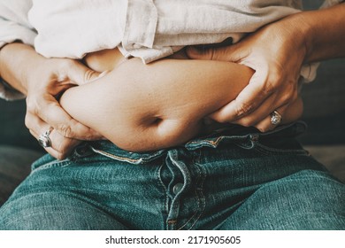 Close Up Of Female Holding Her Belly With Fat. Unhappy Body Positivity Concept. Woman Thinking About Diet. Lazy Lifestyle. Eating Disorder And Unhealthy People. Overeating And Feed. Changes Baby Born