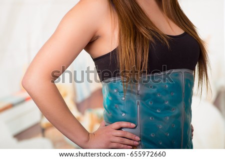 Close up of a female holding ice gel pack on her belly, medical concept, in office background