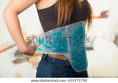 Close up of a female holding ice gel pack on her belly, medical concept, in office background