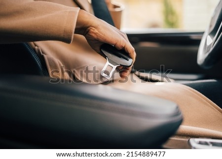 Close up of a female holding a seatbelt, ready to drive.
