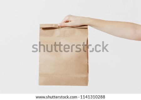 Close up female holds in hand brown clear empty blank craft paper bag for takeaway isolated on white background. Packaging template mock up. Delivery service concept. Copy space. Advertising area