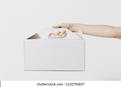 Close Up Female Holds In Hand Cake Dessert In Unmarked Clear Empty Blank Cardboard Box, Food Order Isolated On White Background. Delivery Concept. Copy Space Advertising Area Receiving Package Mock Up