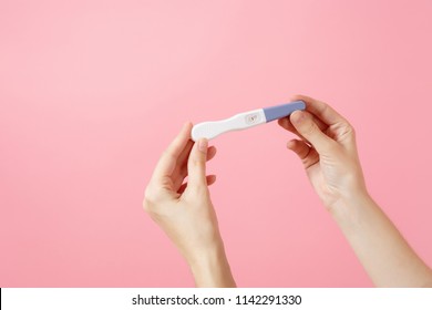 Close up female holds in hands pregnancy test isolated on trending pink background. Medical healthcare gynecological, pregnancy fertility maternity people concept. Nobody. Copy space advertisement