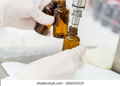 Close up of female lab worker hand with gloves filling the bottle with syrup.