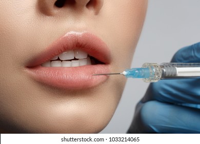 Close up of female lips having hyaluronic acid lifting by syringe. Beauty concept