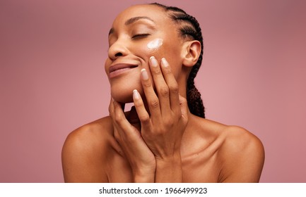 Close up of a female model applying moisturizer to her face. African american woman applying moisturizer cream on her face. - Powered by Shutterstock