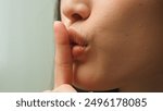 Close up female mouth Asian chinese korean japanese girl unrecognizable woman showing hush lips secret silence quite secrecy confidential mysterious whisper silent hand gesture face details in studio