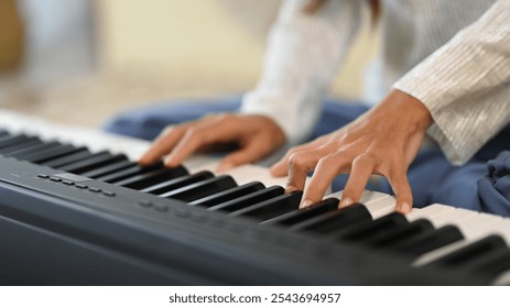 Close up female musician playing an electronic piano in living room - Powered by Shutterstock