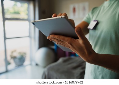 Close Up Of Female Physiotherapist Scrolling On Digital Ipad Standing In Rehab Studio.