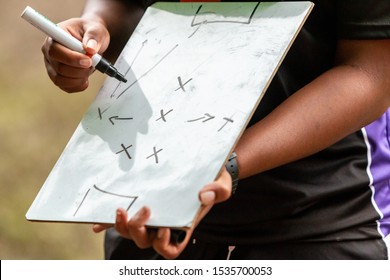 Close up of Female sport coach hand writing game plan on small whiteboard in the field before the game - Powered by Shutterstock