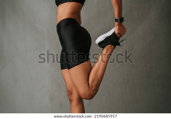 Close up of a female stretching her quadriceps\
muscle holding her black\
sneaker