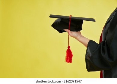 Close Up Of Female Student Holding Mortarboard On Hand Palm. Girl Wearing Graduate Gown, Showing Graduate Cap, Graduating From College. Isolate Don Green Studio Background,